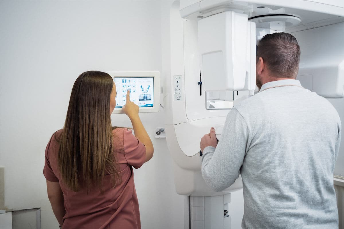 Nurse using the practice's CT scanner with a dental patient