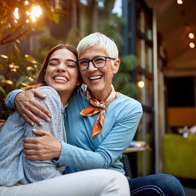 Two women smiling together, both with porcelain veneers